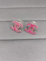Pink and silver earrings on a gray surface