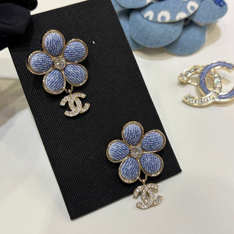 Blue flower-shaped earrings with Chanel logo on a black card