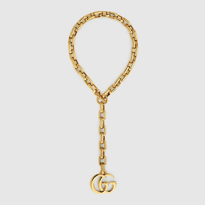 Gold chain bracelet with Gucci logo on a light gray background
