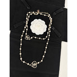Pearl necklace with a white flower brooch on a black outfit