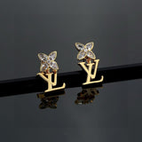 Gold earrings with butterfly designs on a reflective black surface