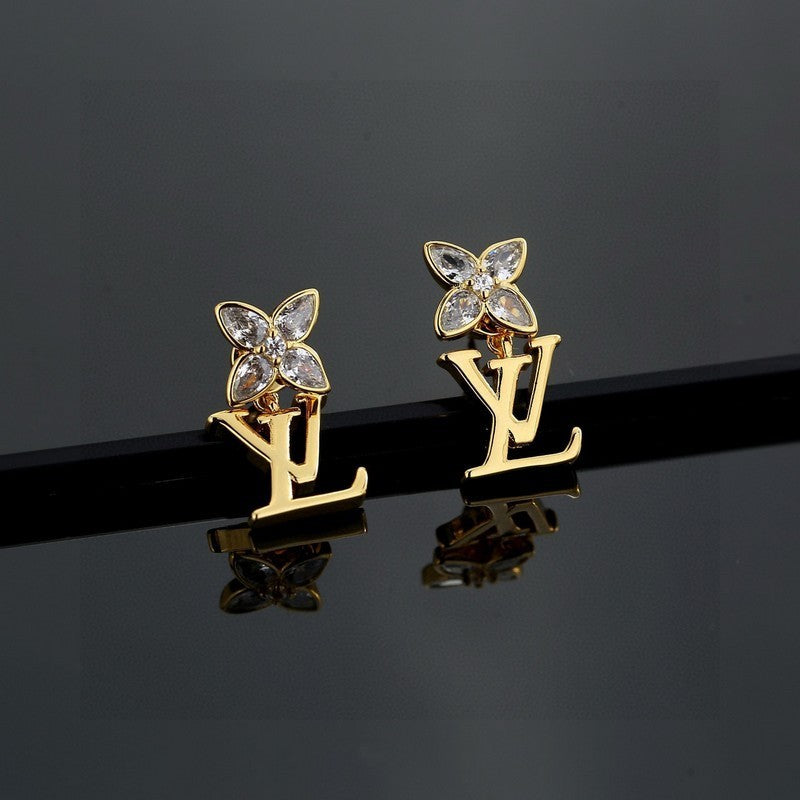 Gold earrings with butterfly designs on a reflective black surface