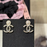 Gold earrings with a logo on a black card, blurred background