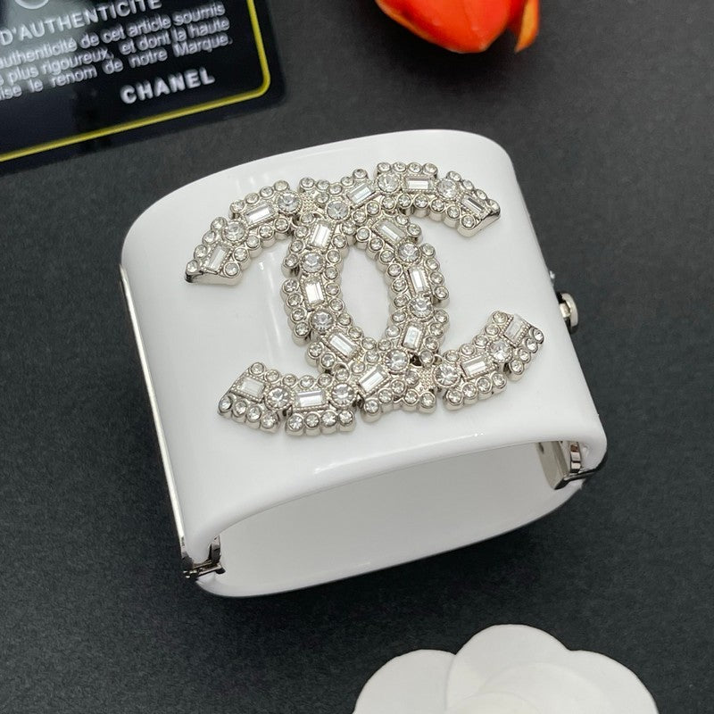 White jewelry box with Chanel logo embellished with crystals on a dark surface.