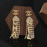 Gold Chanel earrings with diamond accents on a wooden stand against a dark background