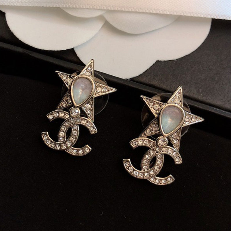 Pair of star-shaped earrings with gemstones on a black surface.