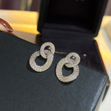 Pair of silver hoop earrings with gemstones on a black surface