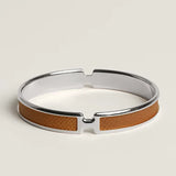 Silver bracelet with brown leather strap on a light gray background